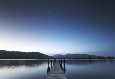 Pier over lake against clear sky at night