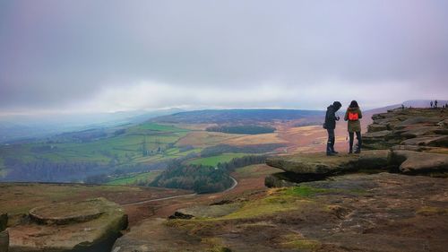 Rear view of men standing on mountain against sky