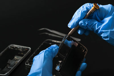 Technician repairing the smartphone's motherboard in the lab with copy space.