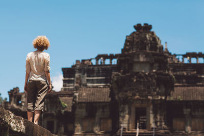 Rear view of woman standing outside historic temple