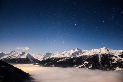 Scenic view of snowcapped mountain range against blue starry sky