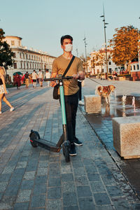 Young man riding an electric scooter in the city center. man wearing the face mask to avoid virus