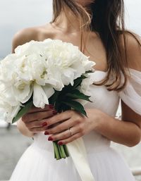 Midsection of bride holding white bouquet during wedding ceremony