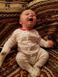 Cute baby girl lying on bed at home