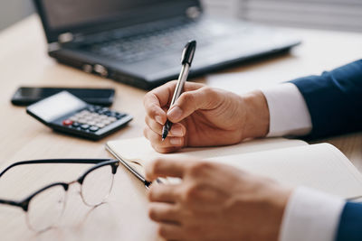 Midsection of man using mobile phone on table