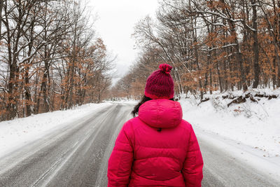 Rear view of woman on snow covered road