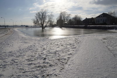 Scenic view of frozen canal by buildings against sky during winter