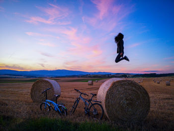 Hay bales on field against sky during sunset