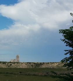 Built structure on landscape against cloudy sky