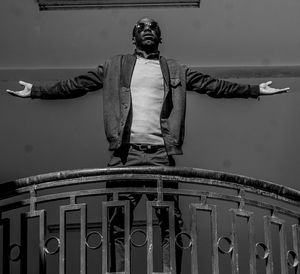 Low angle view of man with arms outstretched standing on balcony