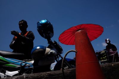 Low angle view of people against clear blue sky