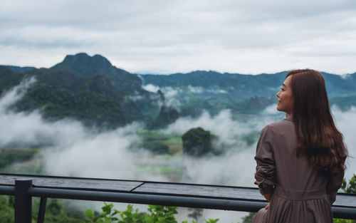 Young woman looking at mountains against sky
