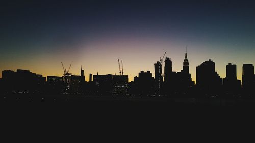 Silhouette of city against clear sky during sunset