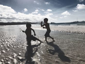 Children on beach against sky