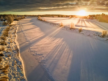Scenic view of snow covered land against sky during sunset