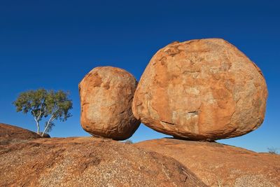 Low angle view of devils marbles against clear blue sky