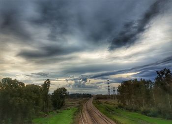 Empty road along plants and trees against sky