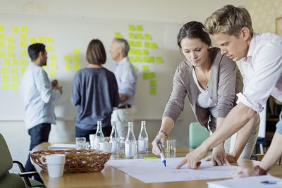 Business people discussing over blueprint at conference table