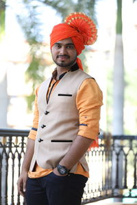 Portrait of young man standing against railing