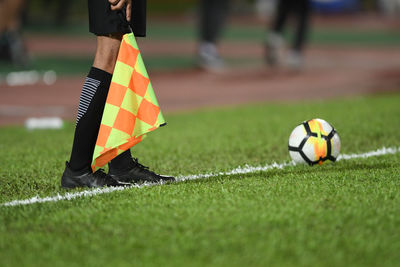 Low section of male referee holding flag while standing on soccer field