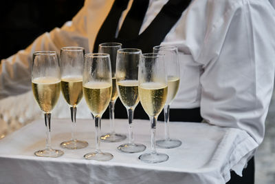 Midsection of waiter serving champagne on tray