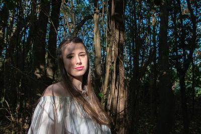 Portrait of young woman standing in forest