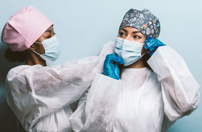 Doctors wearing mask standing against colored background