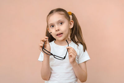 Portrait of young woman holding stethoscope against pink background