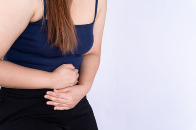 Midsection of woman touching hair over white background