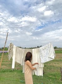 Rear view of woman standing on field against sky