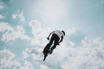 Low angle view of man performing stunt with bicycle against sky