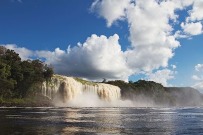 View of waterfall against cloudy sky