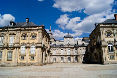 Buildings in city against cloudy sky during sunny day