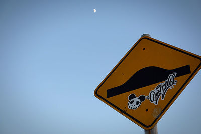 Low angle view of road sign against clear blue sky