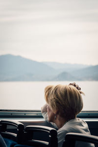 Rear view of man and woman by car against lake