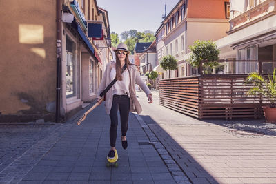 Portrait of teenage girl skateboarding on footpath