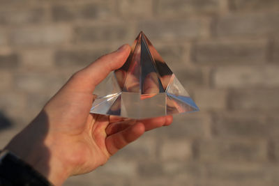 Close-up of hand holding crystal against wall