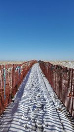 View of empty road against clear blue sky