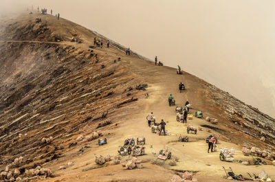 People working on mountain against sky