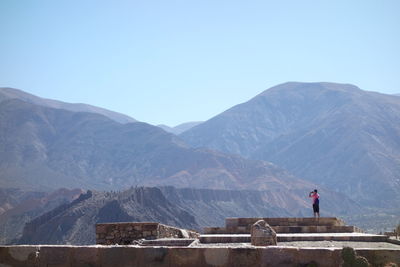 Rear view of people on mountain against clear sky