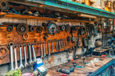 Old workshop with tools. wrenches and grinding wheel hang on wall. repair items on table and shelve