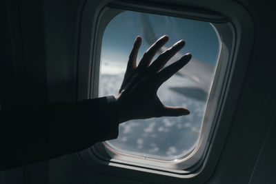 Cropped silhouette hand on airplane window