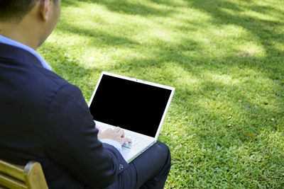 Midsection of man using mobile phone in grass