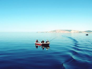 Boats in calm sea against clear sky