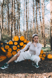 Portrait of young woman sitting on log in forest