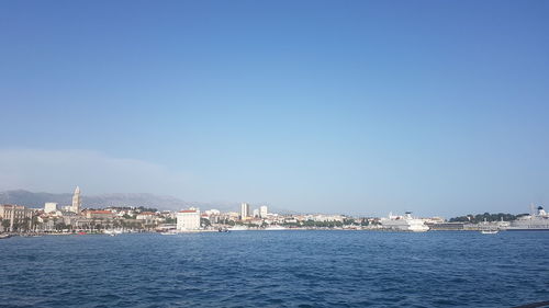 Sea by buildings against clear blue sky