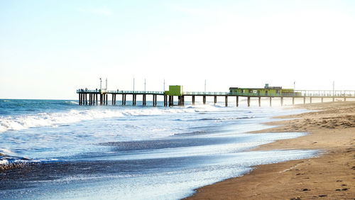 Pier on beach against clear sky