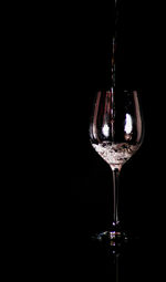 Close-up of wineglass on glass against black background