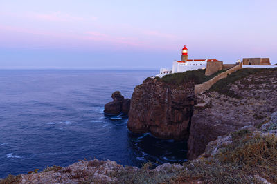 Lighthouse by sea against sky