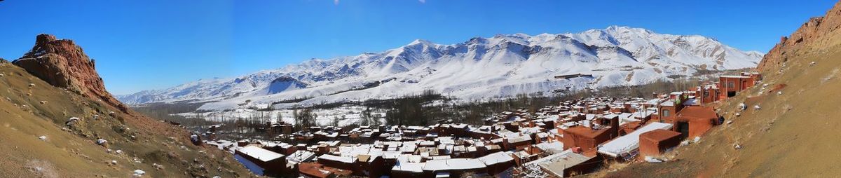 Panoramic view of people on snowcapped mountains against clear blue sky